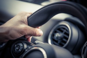 Detail of a hand holding a steering wheel.